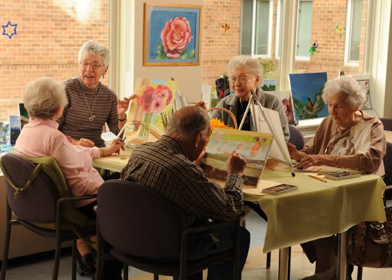 A group of seniors engaged in a painting class, working on their individual art pieces.