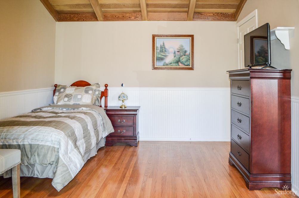 A cozy bedroom with wooden furniture and flooring.