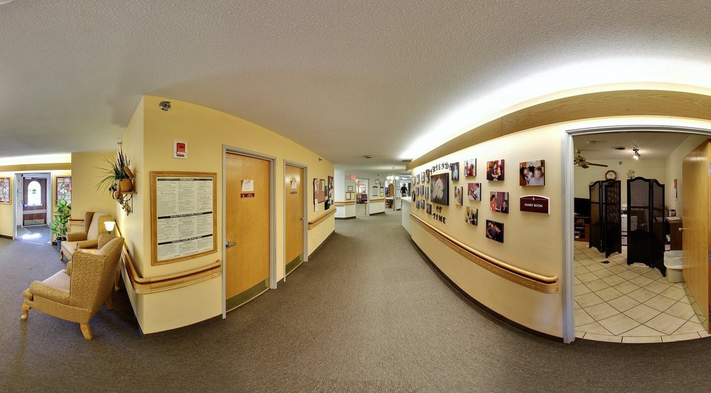 A well-lit hallway with doors and photographs displayed on the walls.