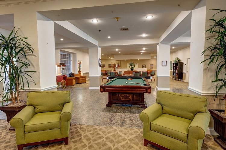 A spacious community lounge featuring a pool table and comfortable seating areas.