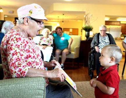 A heartwarming moment of connection between a child and an elderly woman as they share a story in a care home.