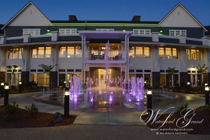 Illuminated hotel entrance with a colorful fountain at dusk.