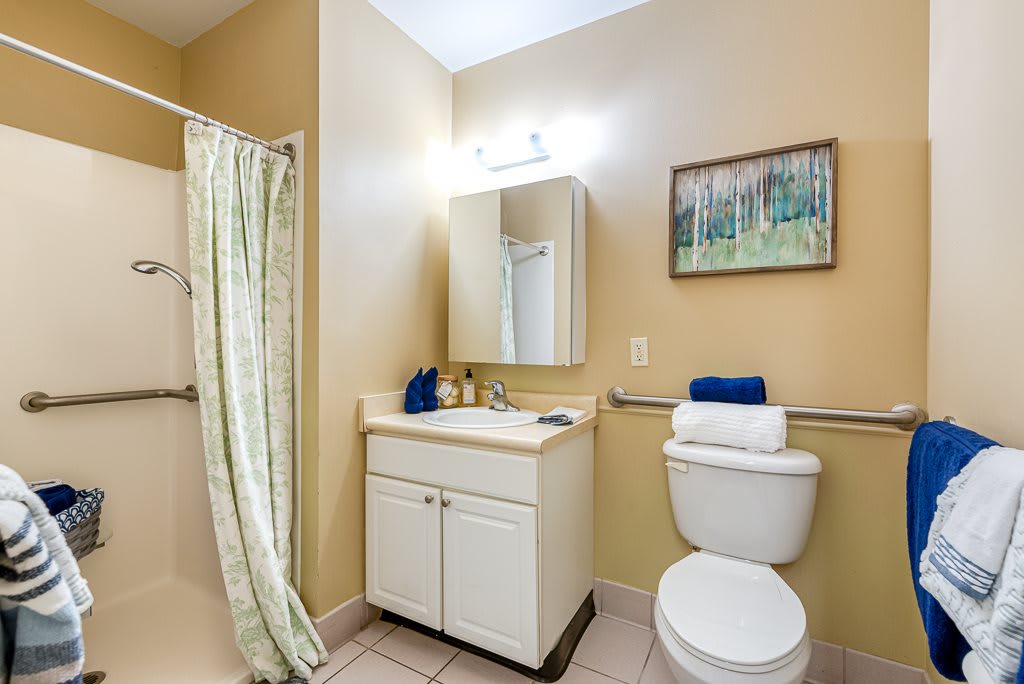 A clean and organized bathroom featuring a shower, sink, mirror, and toilet.