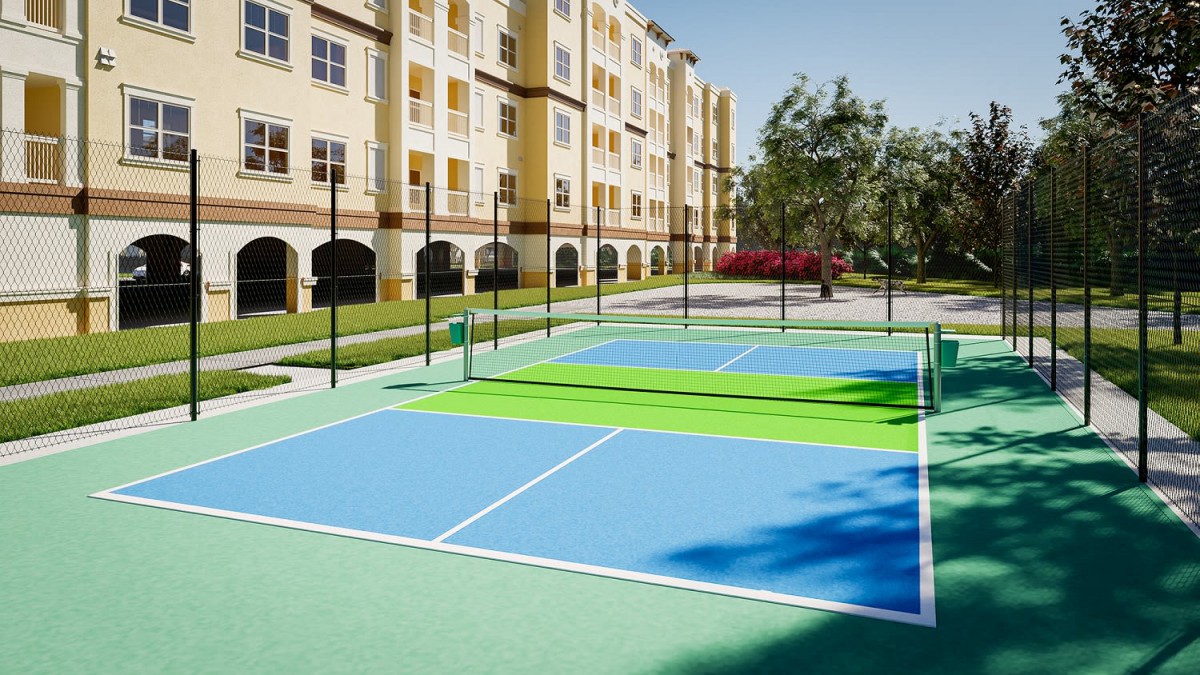 An outdoor tennis court located beside a residential building on a sunny day.