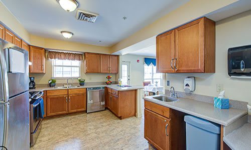 A spacious kitchen with wooden cabinets, modern appliances, and natural light from a window.
