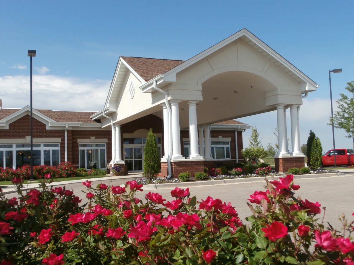 A beautifully landscaped entrance to a building with red flowers in the foreground.