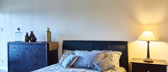 A cozy bedroom featuring a neatly made bed with patterned pillows and a stylish headboard.