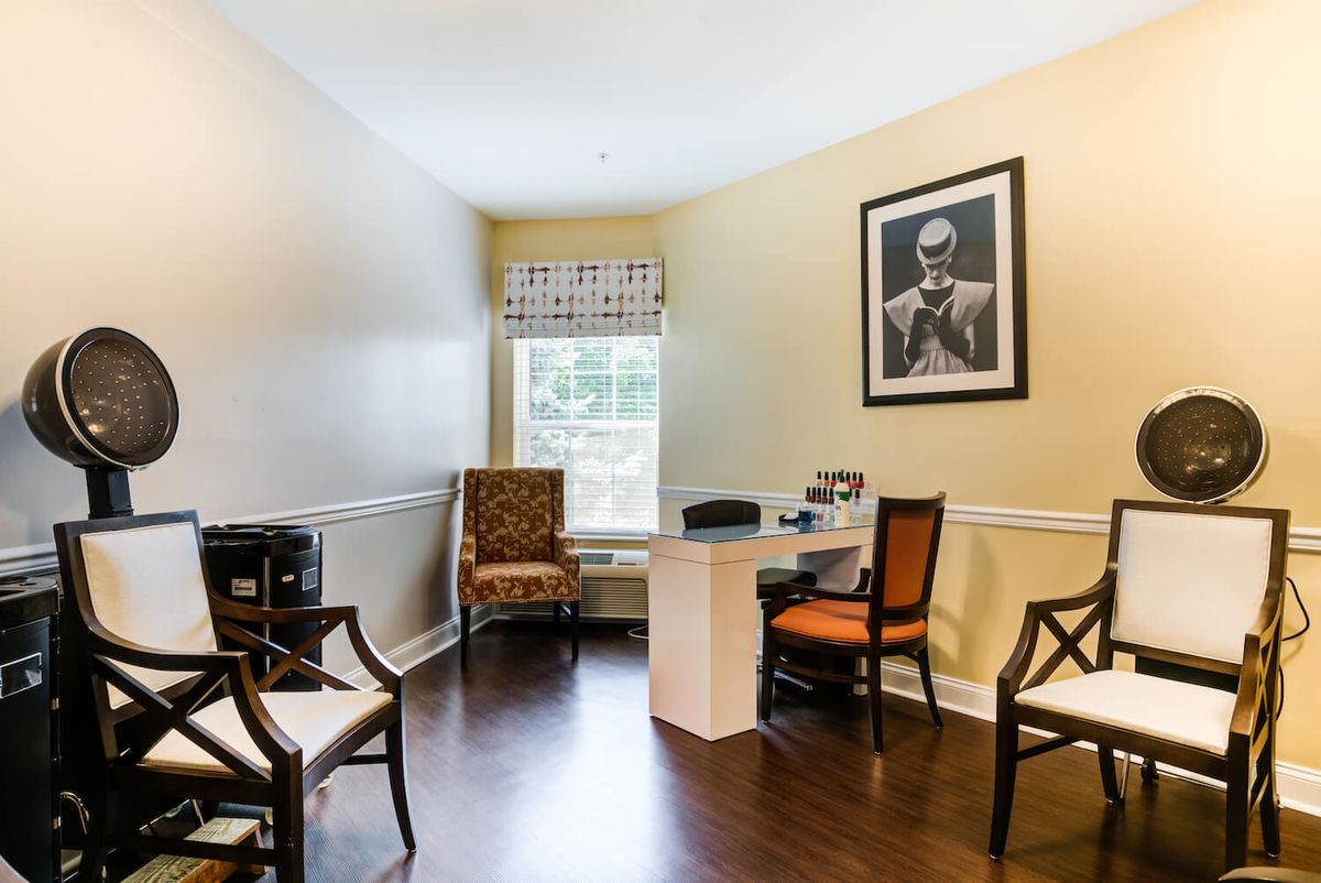 A small office space featuring a desk, several chairs, and artwork on the wall.