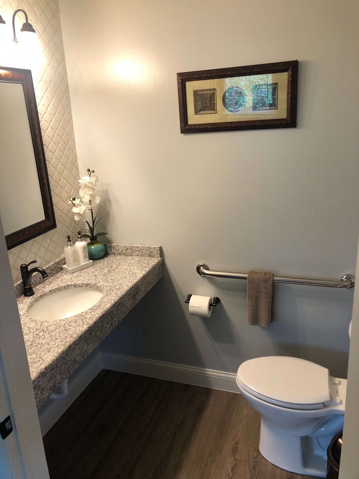 A small bathroom with a sink, toilet, and a decorative framed picture on the wall.