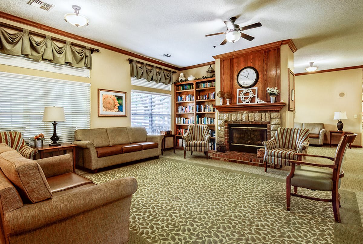 A cozy living room with a fireplace, sofas, armchairs, and bookshelves.