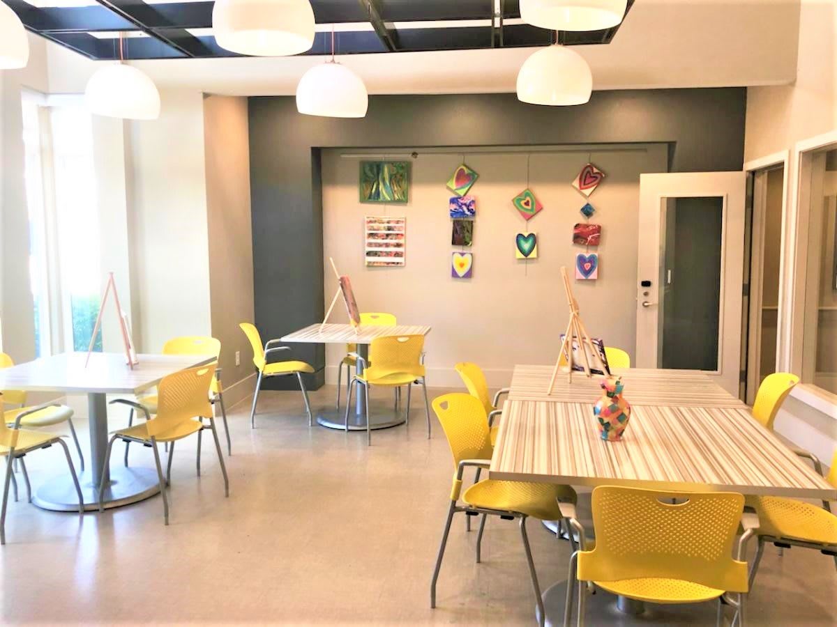 A bright and modern classroom with yellow chairs and art-adorned walls.
