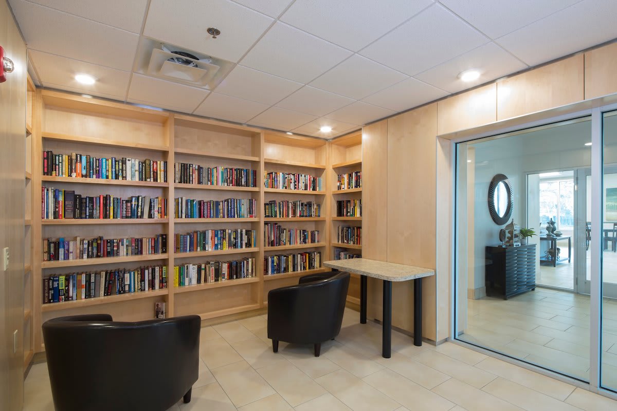 A cozy reading area with bookshelves, seating, and a table.