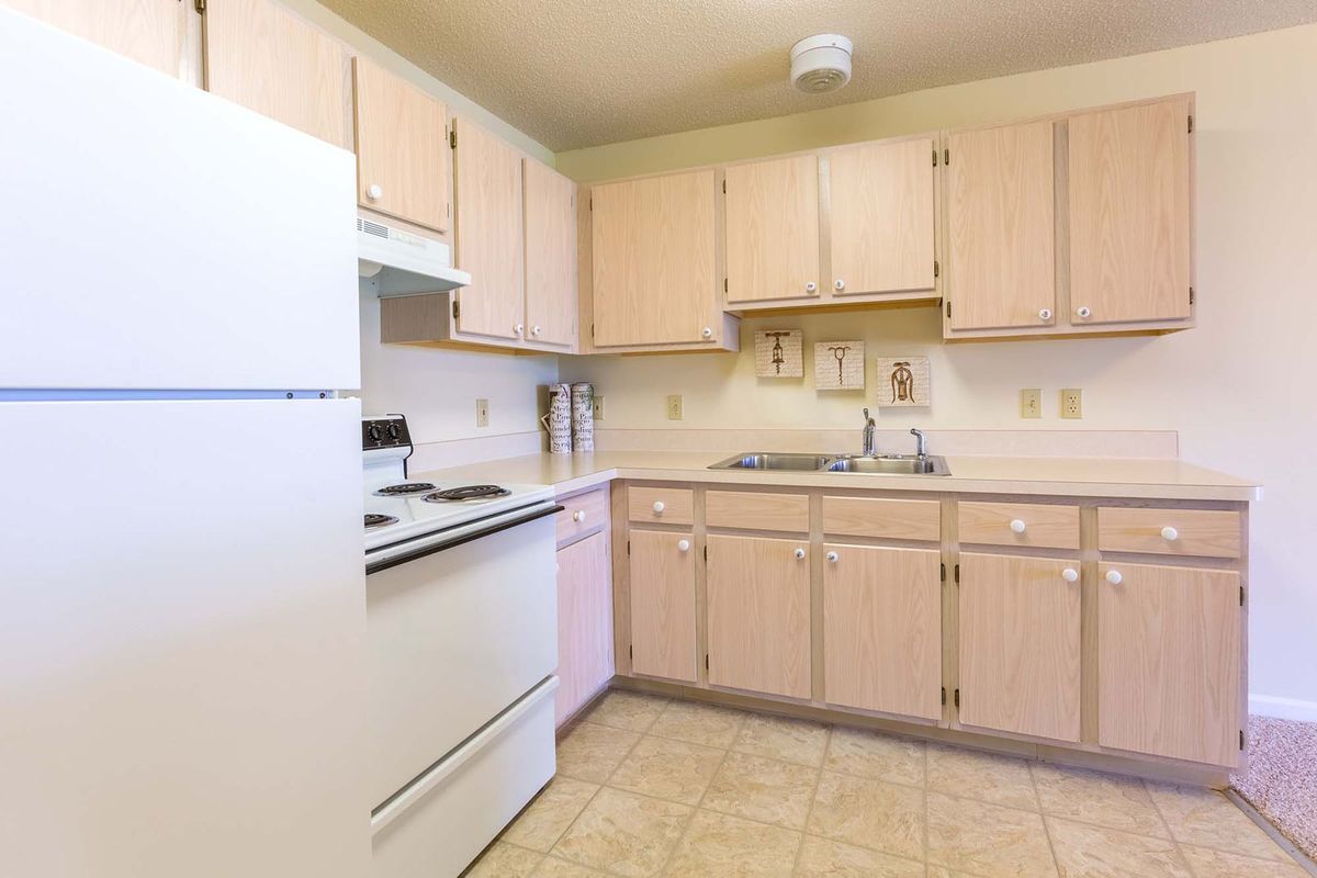 A clean and minimalistic kitchen with light wooden cabinets and standard appliances.