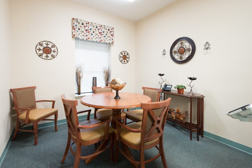 A cozy dining room with a round wooden table and chairs, adorned with wall art and elegant decor.