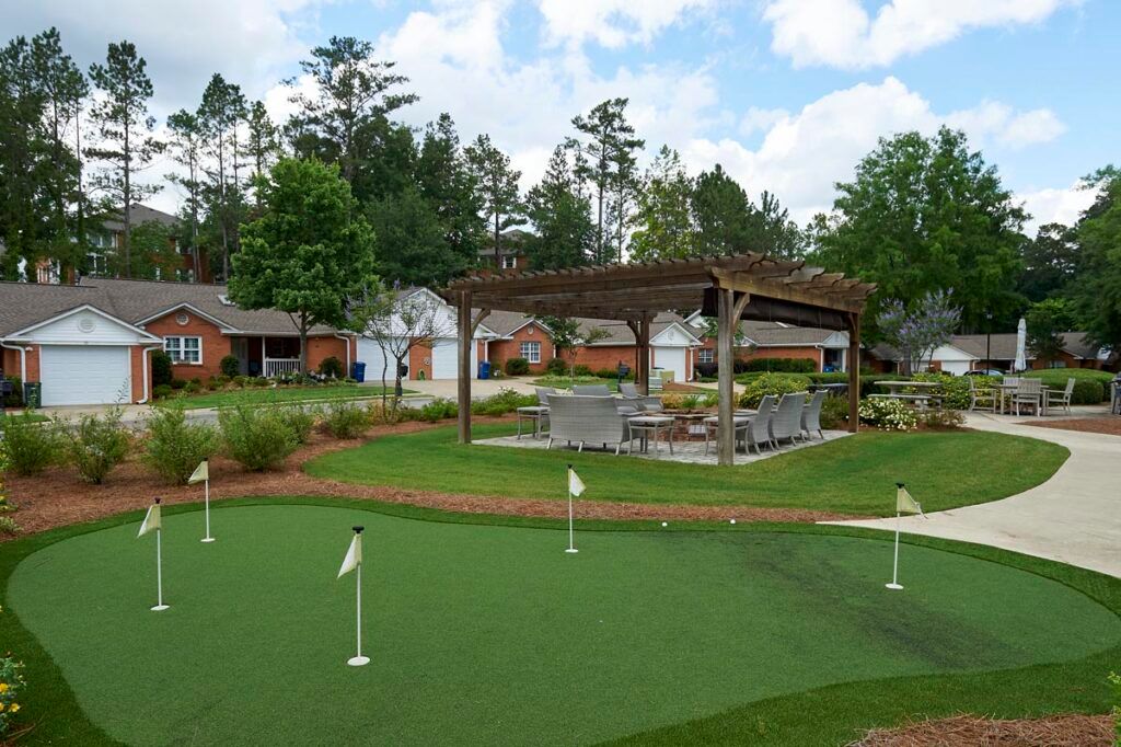 A serene suburban landscape featuring a well-maintained putting green and a pergola.