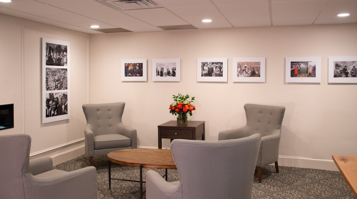 A cozy waiting room with comfortable chairs, a wooden table, and framed pictures on the wall.