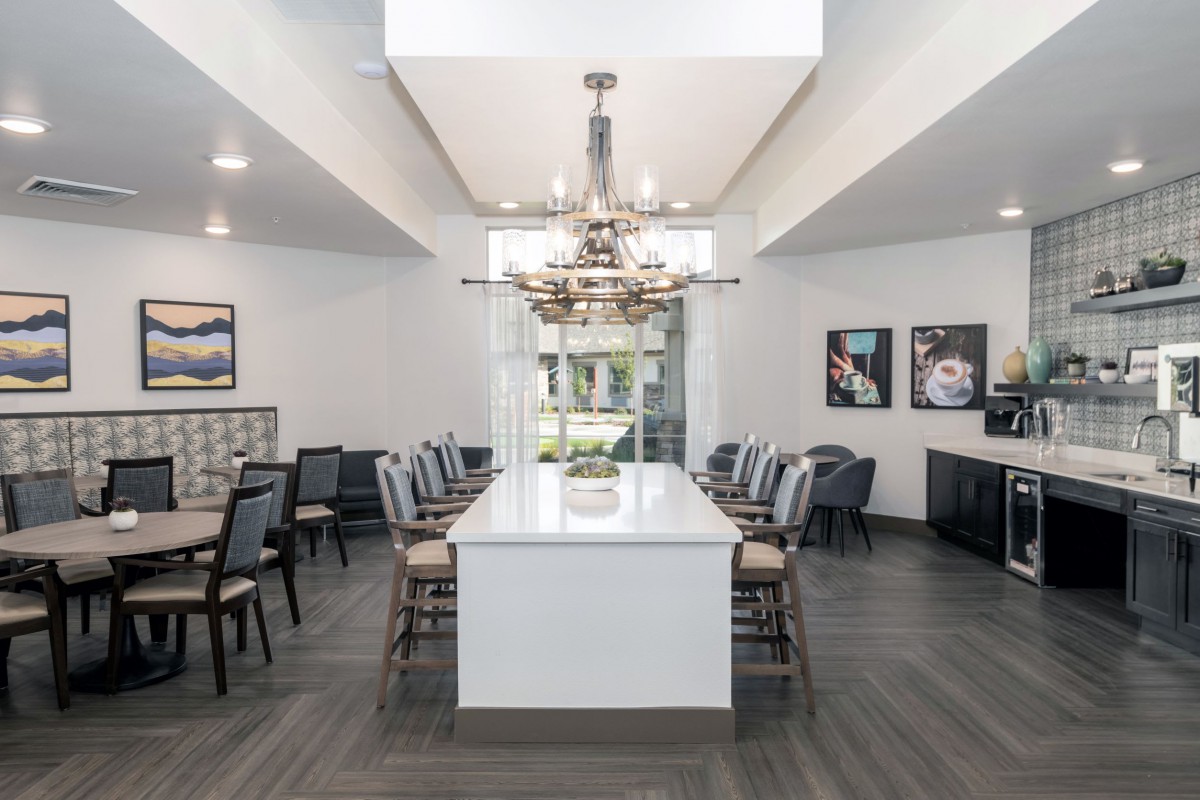 A modern dining room with a central chandelier and ample seating around a long table.