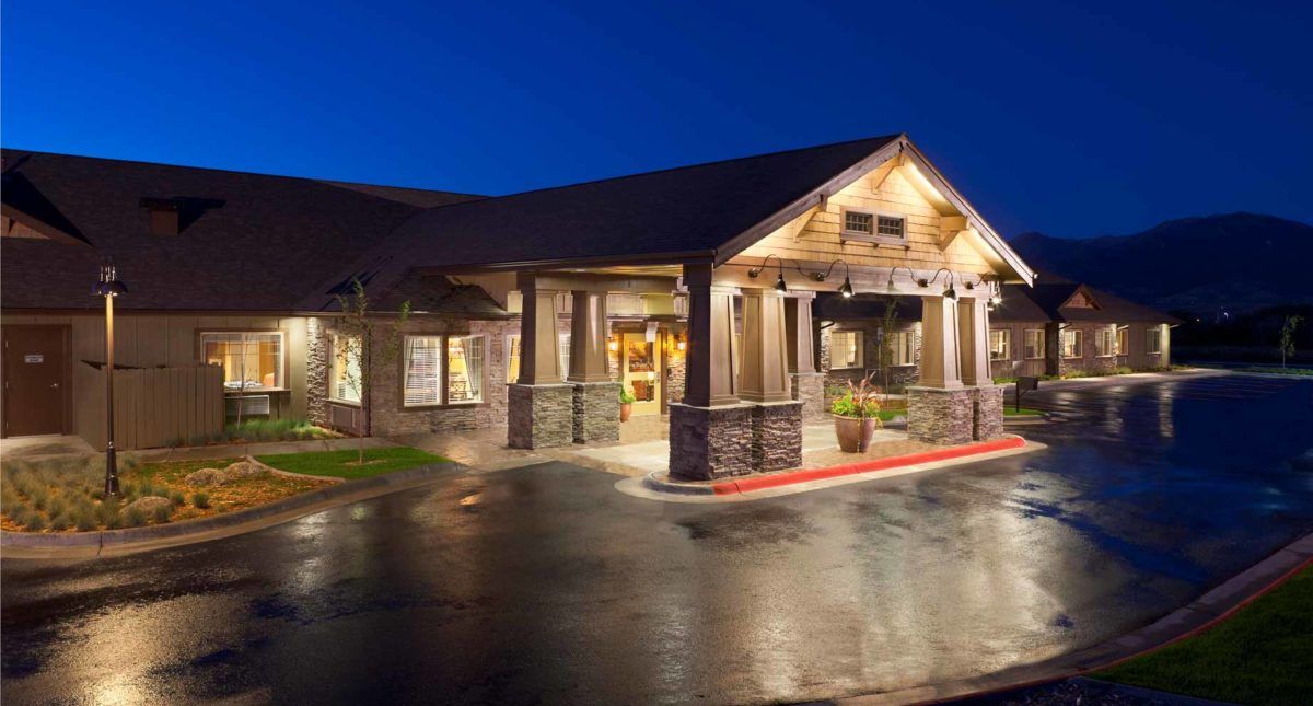 A well-lit building entrance at night with a rustic architectural style.