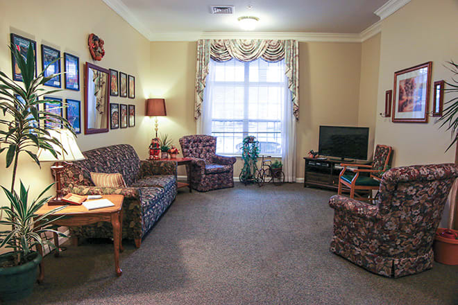 A cozy living room with patterned furniture and a television next to a large window.