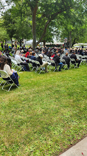 A gathering of people seated on chairs in an outdoor setting.