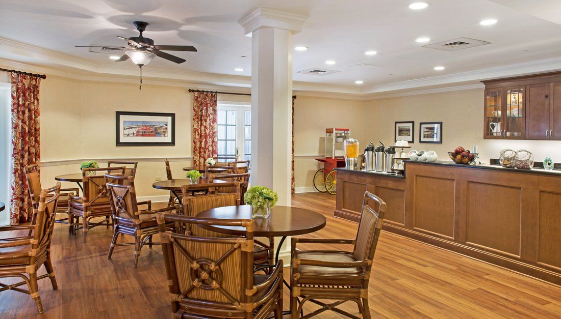 A cozy dining area with wooden tables and chairs, well-lit with natural and ceiling lights.