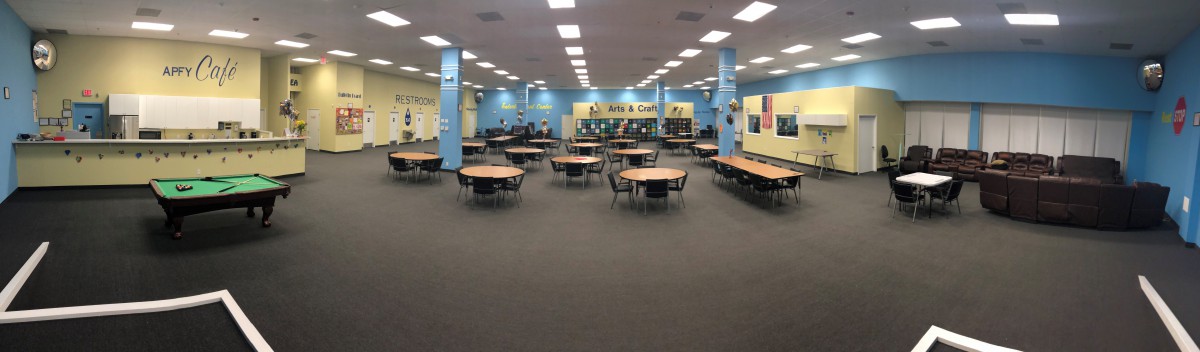 A spacious library with round tables and chairs, surrounded by bookshelves.
