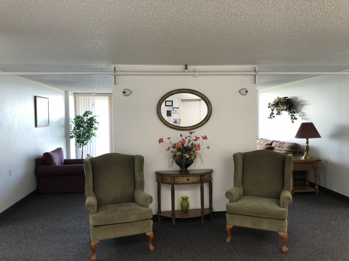 A cozy living room setting with two armchairs, a decorative table, and a mirror adorned on the wall.
