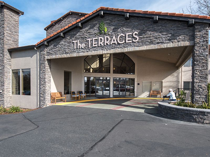 The entrance of 'The Terraces' showcasing its stone facade and welcoming design.