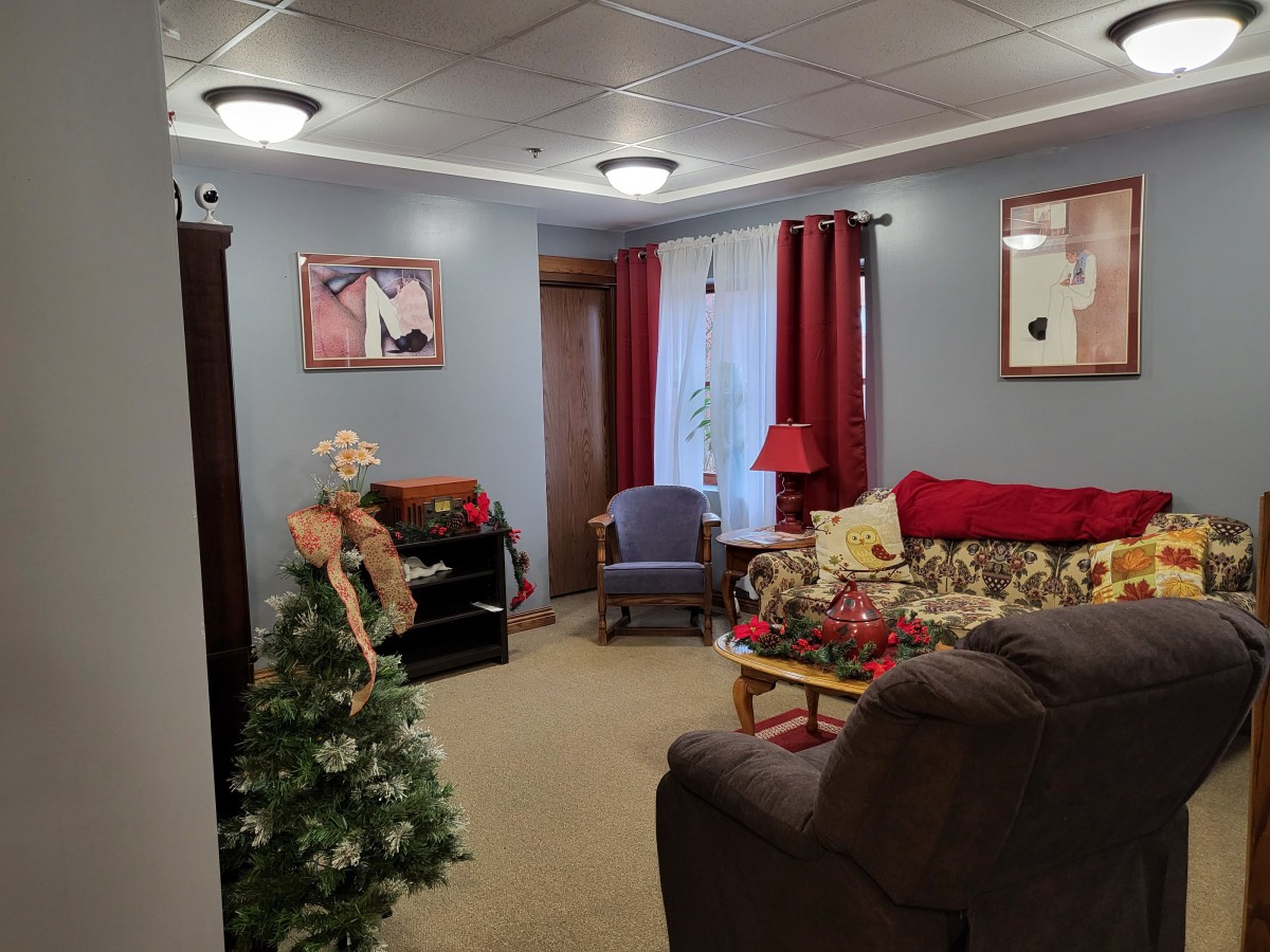 A cozy living room decorated with a small Christmas tree and comfortable furniture.