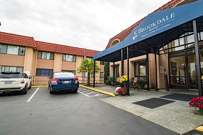 The entrance of a hotel with a car parked outside under an awning.