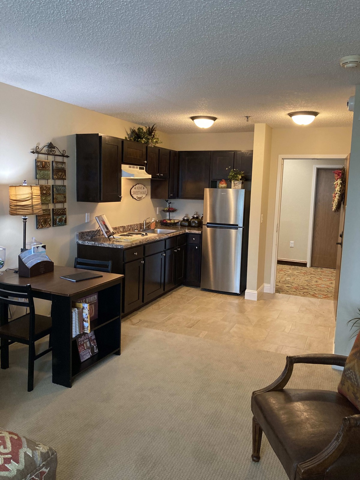 A modern kitchen and dining area in an apartment with dark cabinets and stainless steel appliances.