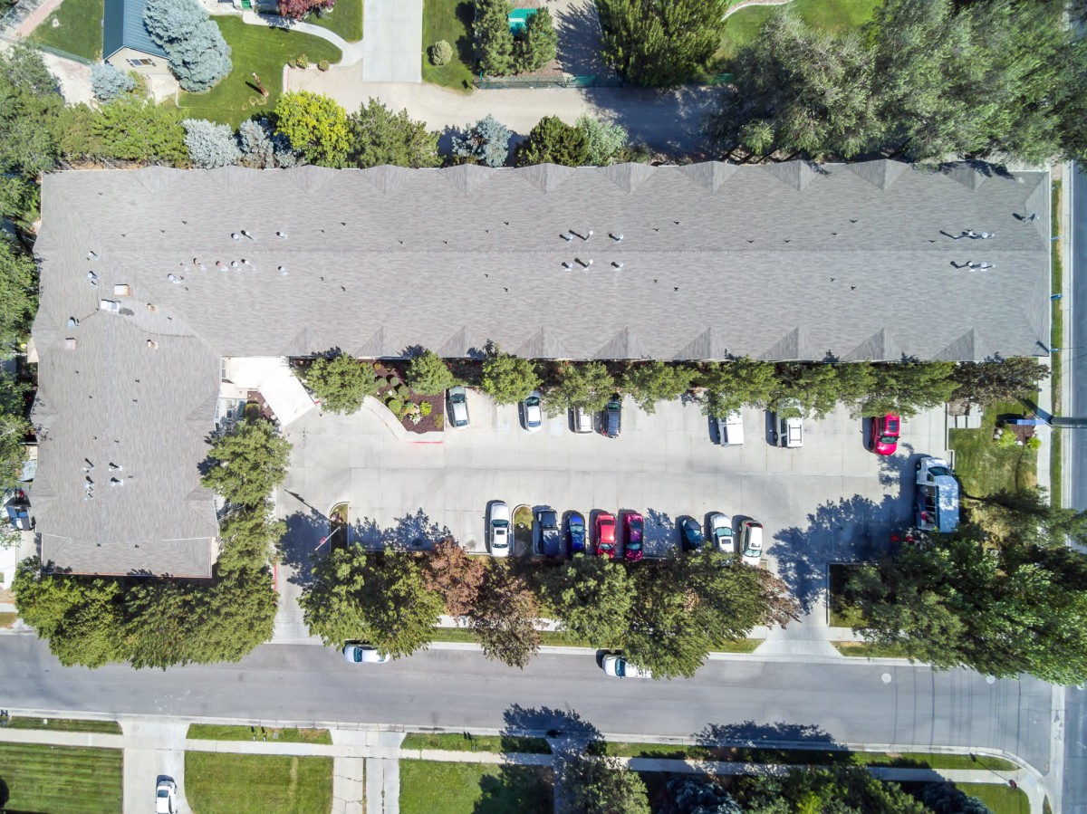 Aerial view of a residential parking lot with several cars and surrounding greenery.