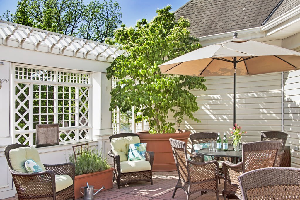 A cozy outdoor patio with comfortable seating and a large umbrella, perfect for enjoying a sunny day.