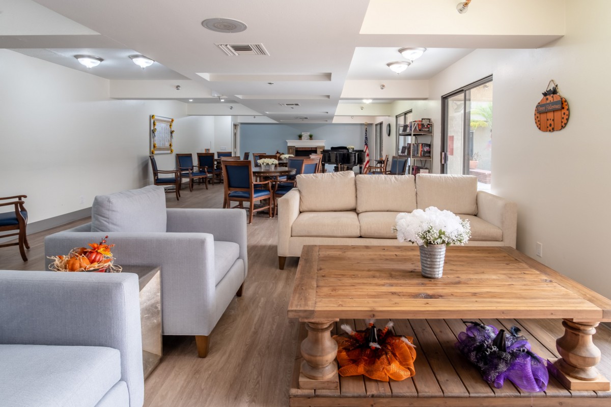 A modern living room with comfortable sofas and a wooden coffee table, decorated with flowers.