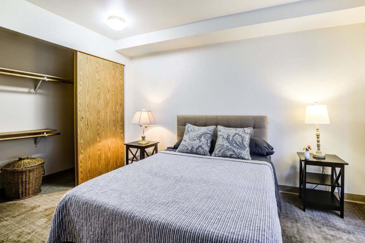 A cozy bedroom with a neatly made bed, nightstands, and a closet.