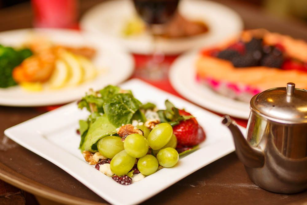 A table setting with a fresh salad and green grapes, accompanied by dessert.