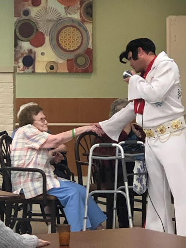 An Elvis impersonator performing for a resident in a care home, creating a joyful moment.