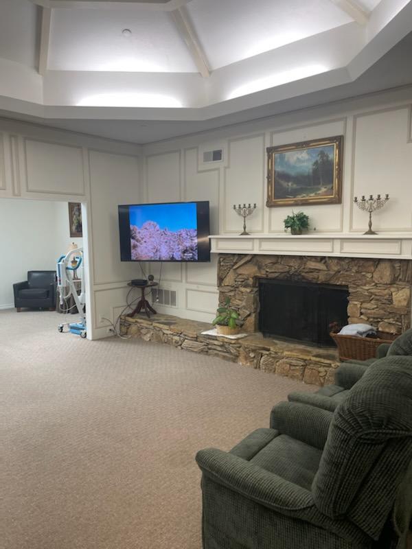 A cozy living room featuring a stone fireplace, wall-mounted television, and comfortable recliner.