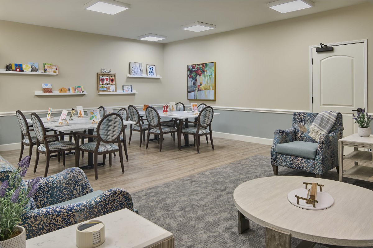 A well-appointed dining area with neatly arranged tables and chairs, complemented by artwork on the wall.