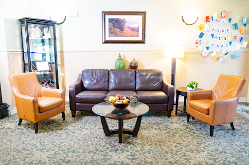 A cozy living room setup featuring a brown sofa, two orange chairs, and a circular coffee table adorned with fruit.