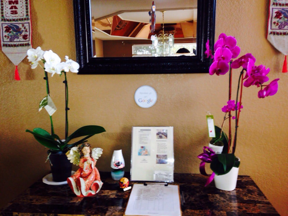 A beautifully arranged table with orchids, an angel figurine, and a mirror.