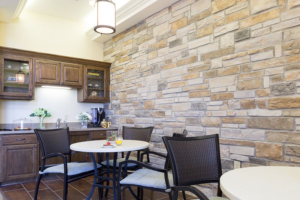 A modern kitchen and dining area featuring a stone accent wall and wooden furniture.