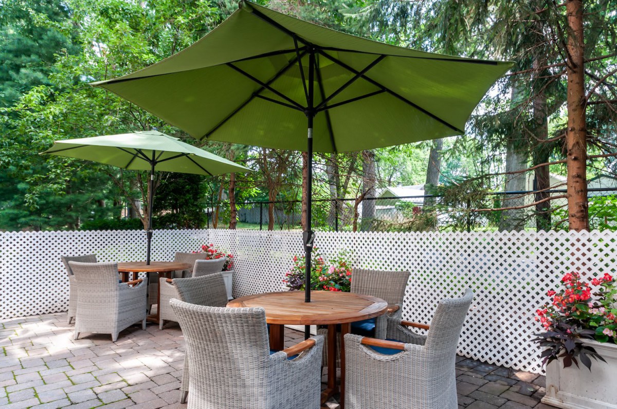 A cozy outdoor patio setting with wicker chairs and a wooden table under a green umbrella.