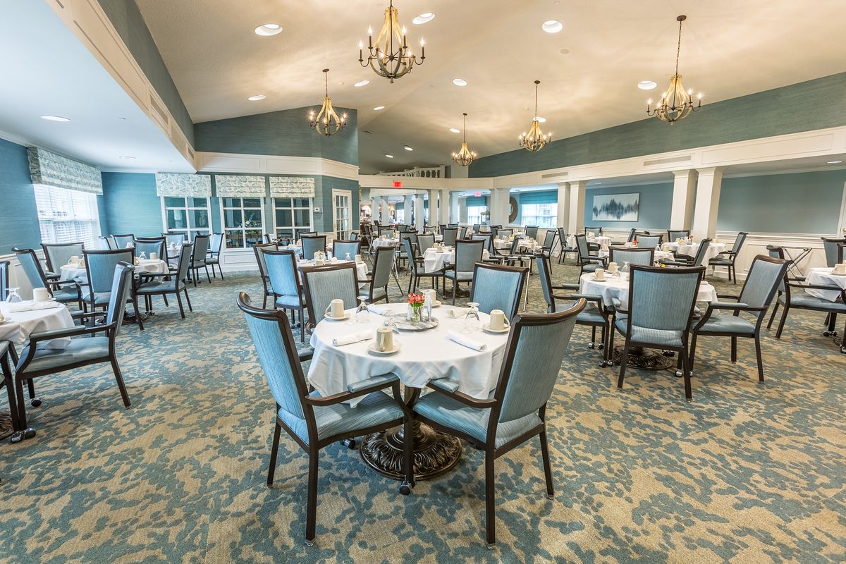 An elegant dining room with neatly arranged tables and chandeliers.