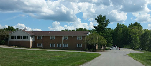 A peaceful residential building surrounded by greenery under a blue sky.