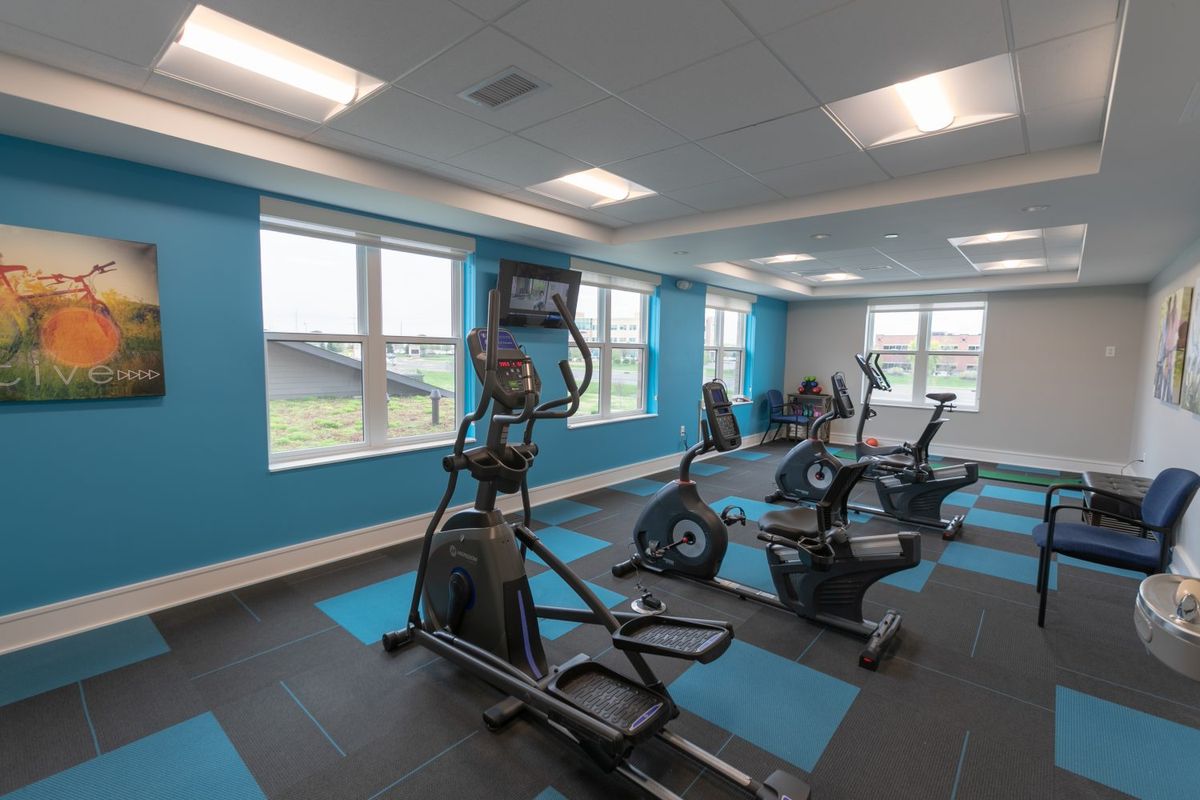 A modern gym with various exercise machines and bright blue walls.