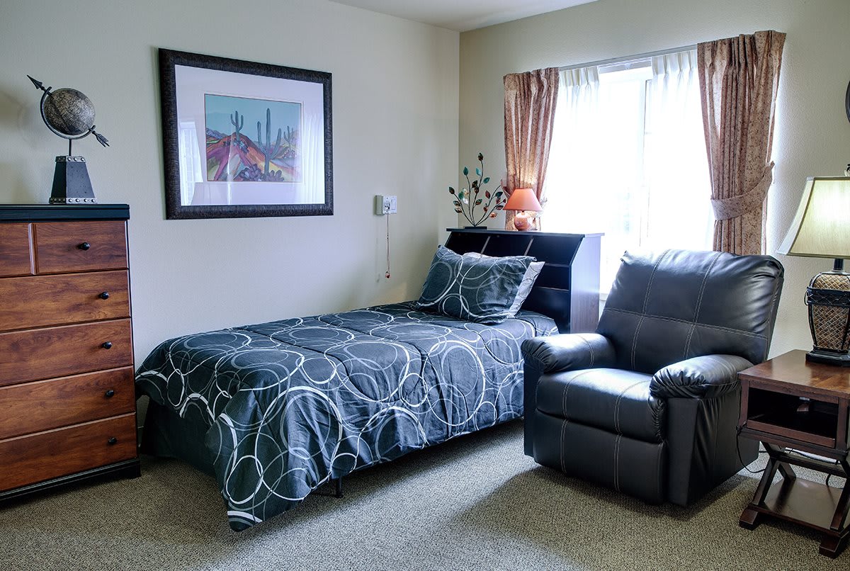 A cozy bedroom with a single bed, armchair, and colorful decor.