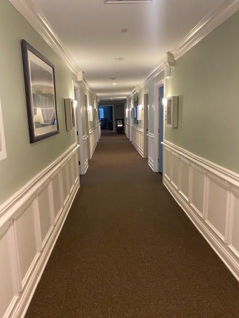 A well-lit interior hallway featuring doors on either side and a carpeted floor.