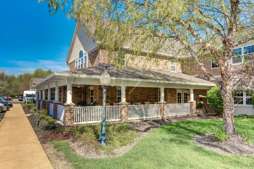 A spacious residential house with a wraparound porch and well-maintained landscaping.