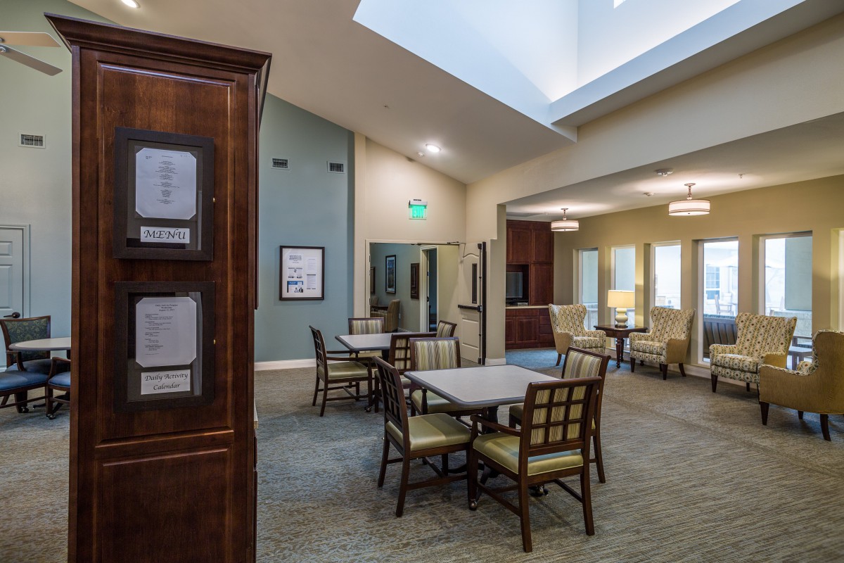 A modern and spacious room with tables and chairs arranged neatly, featuring ample lighting.
